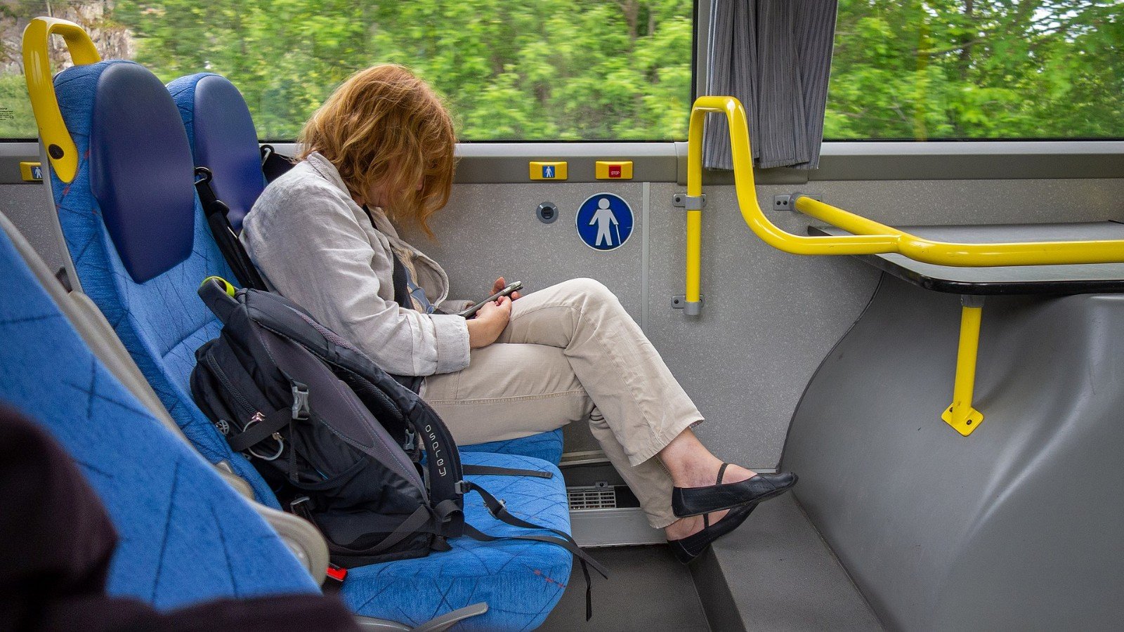 A person checking a smartphone while riding a bus.
