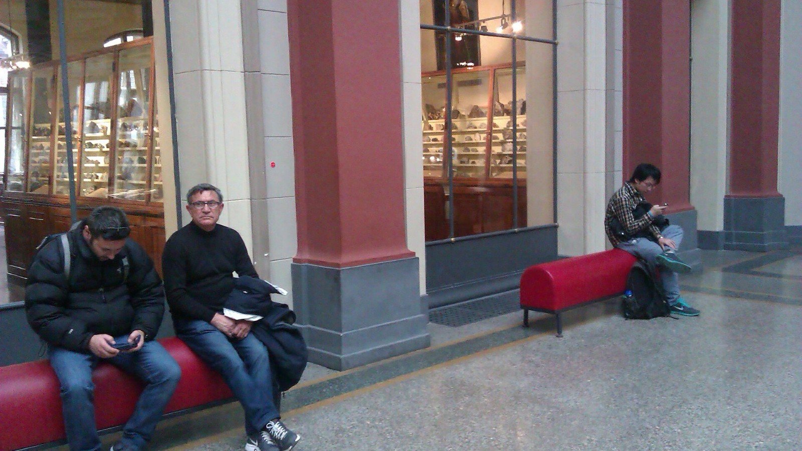 Visitors using smartphones inside a museum, illustrating how mobile apps access device features.